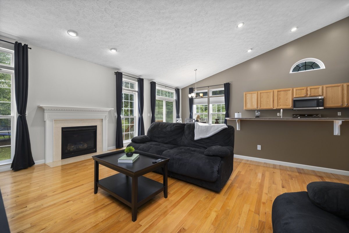 Great room with vaulted ceiling, gas-log fireplace, and sightline to the kitchen