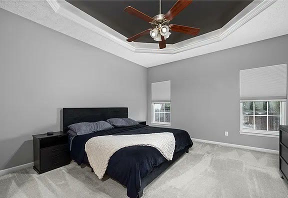 Primary bedroom with tray ceiling and ceiling fan